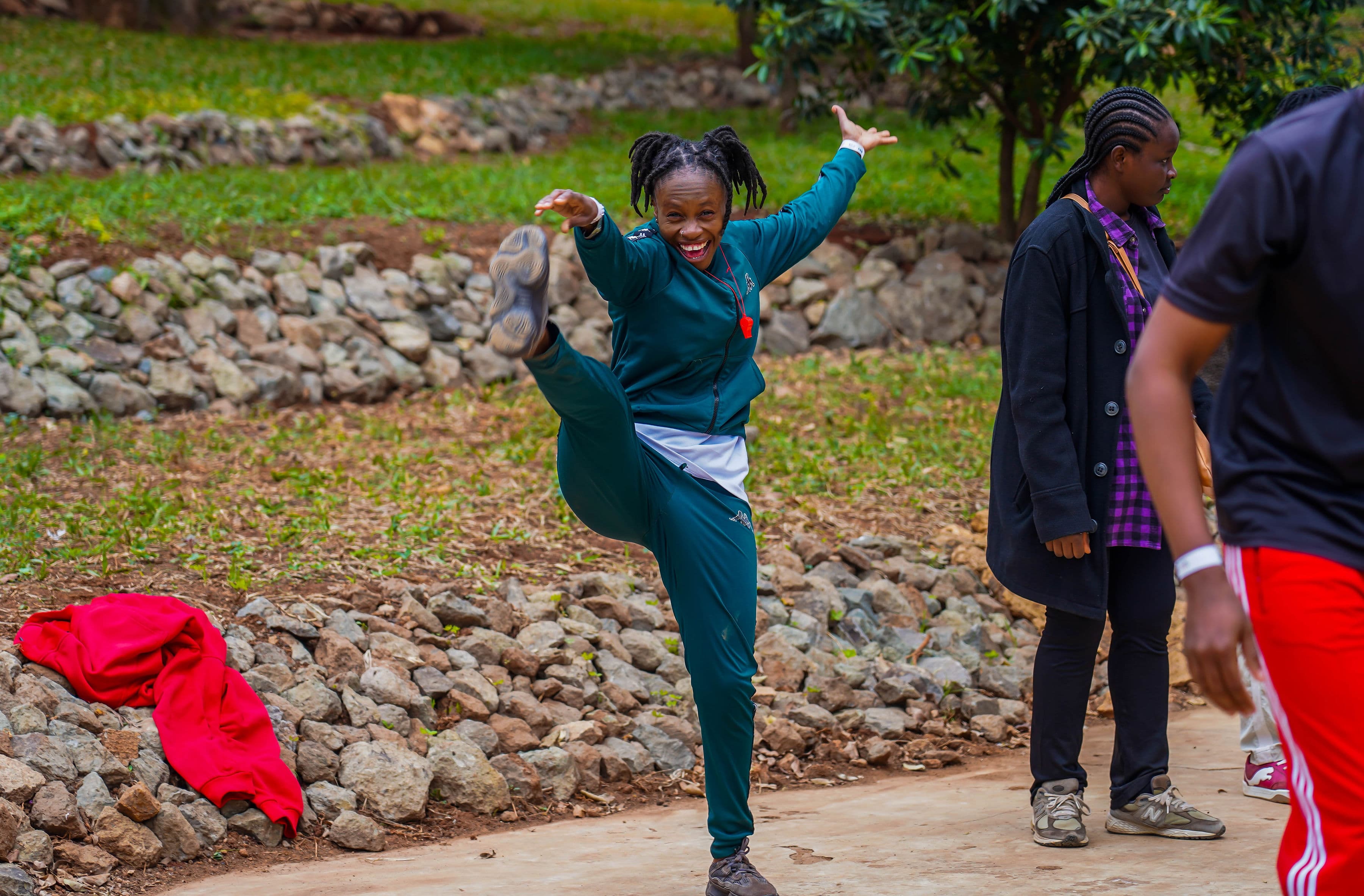 A woman laughing and kicking up her leg on a path, arms raised