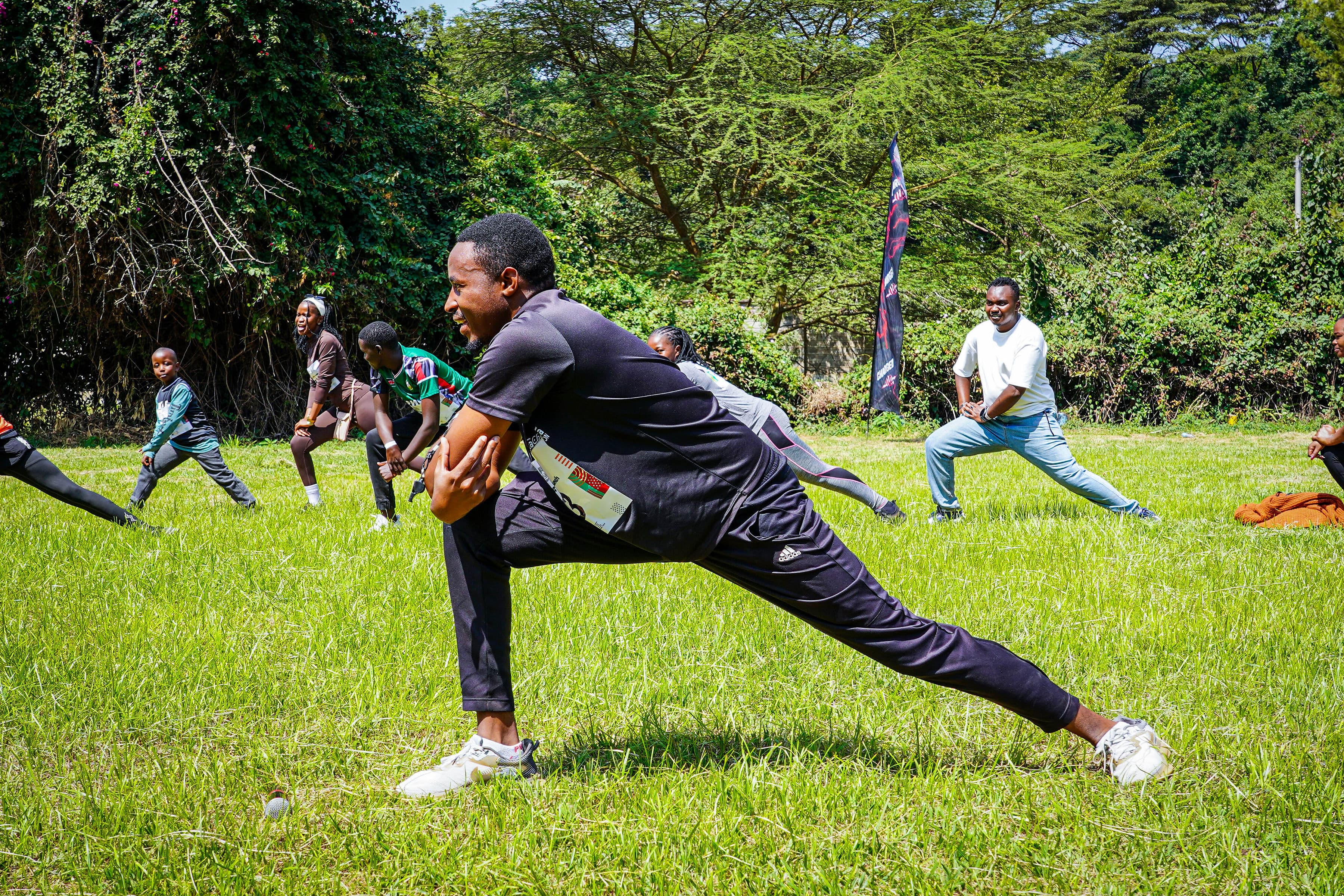 A group stretching in a lunge outdoors on the grass