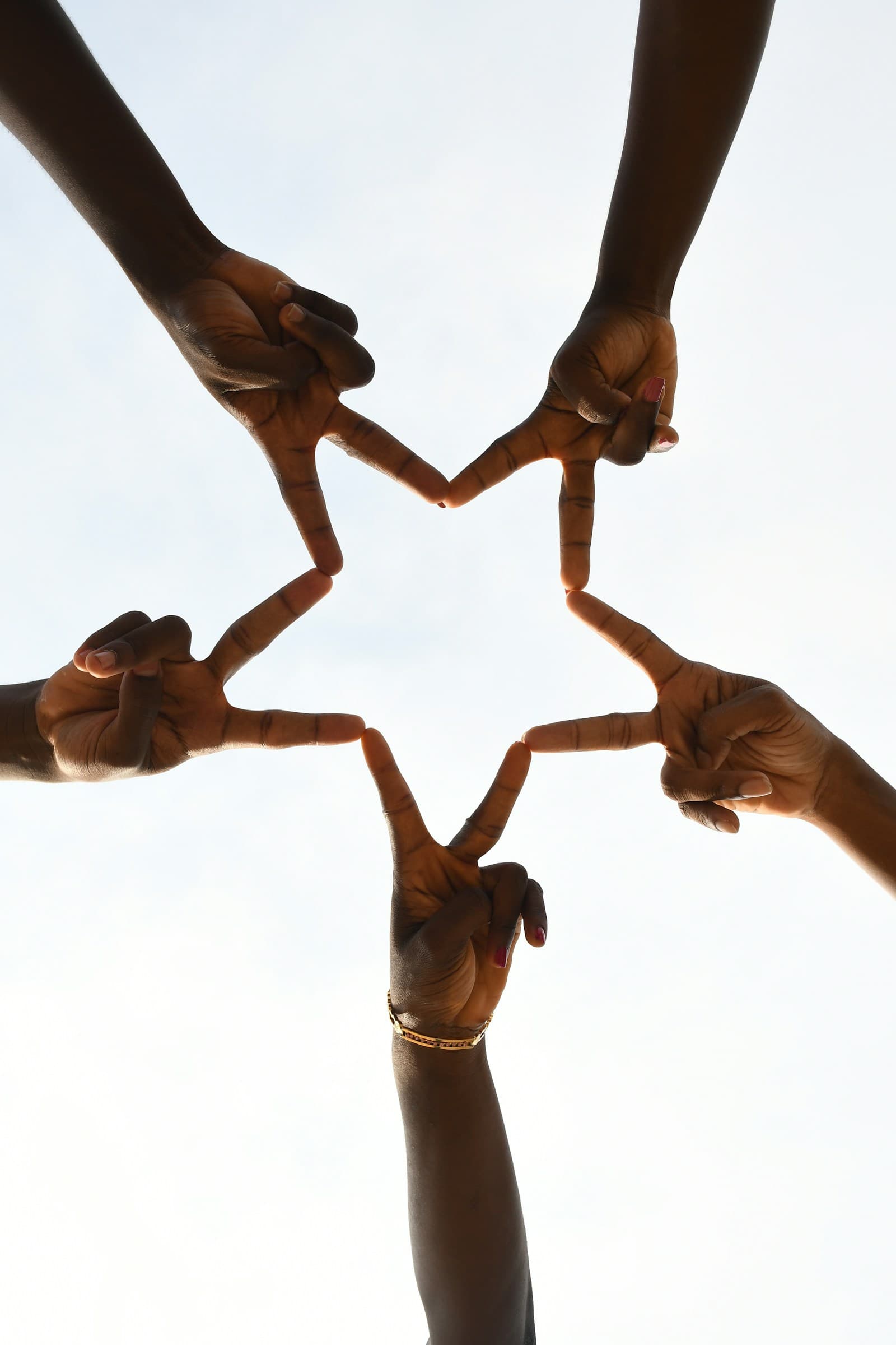 A circle of hands forming a star overhead, symbolising communal healing and togetherness.
