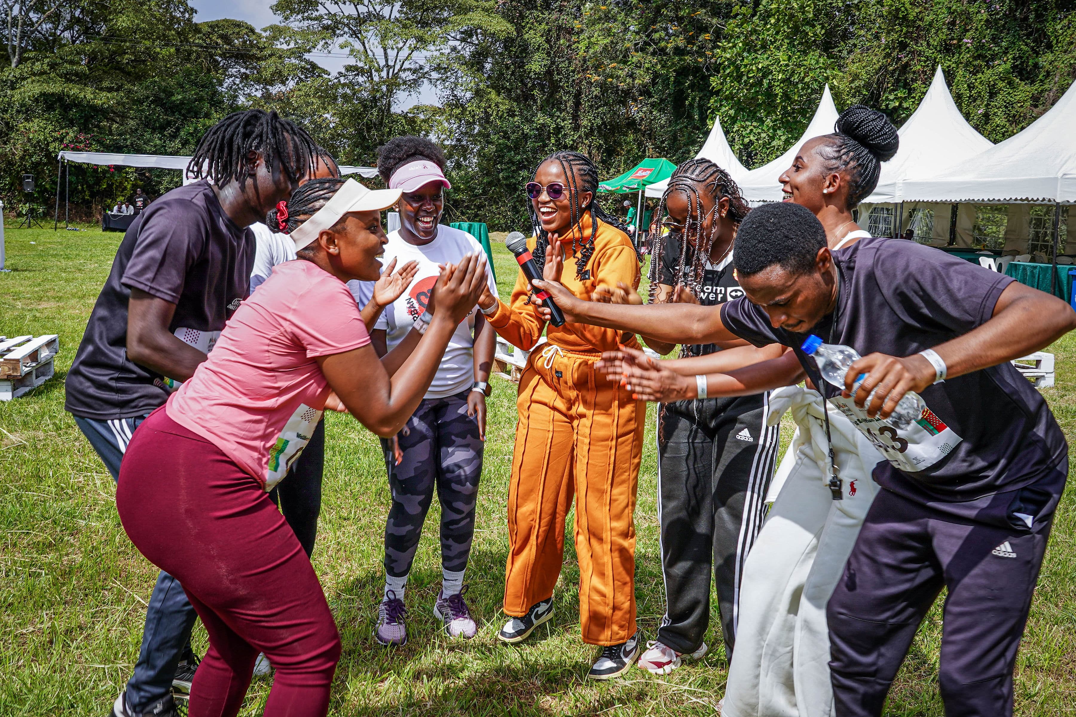 Participants laughing and high-fiving in a circle on the grass