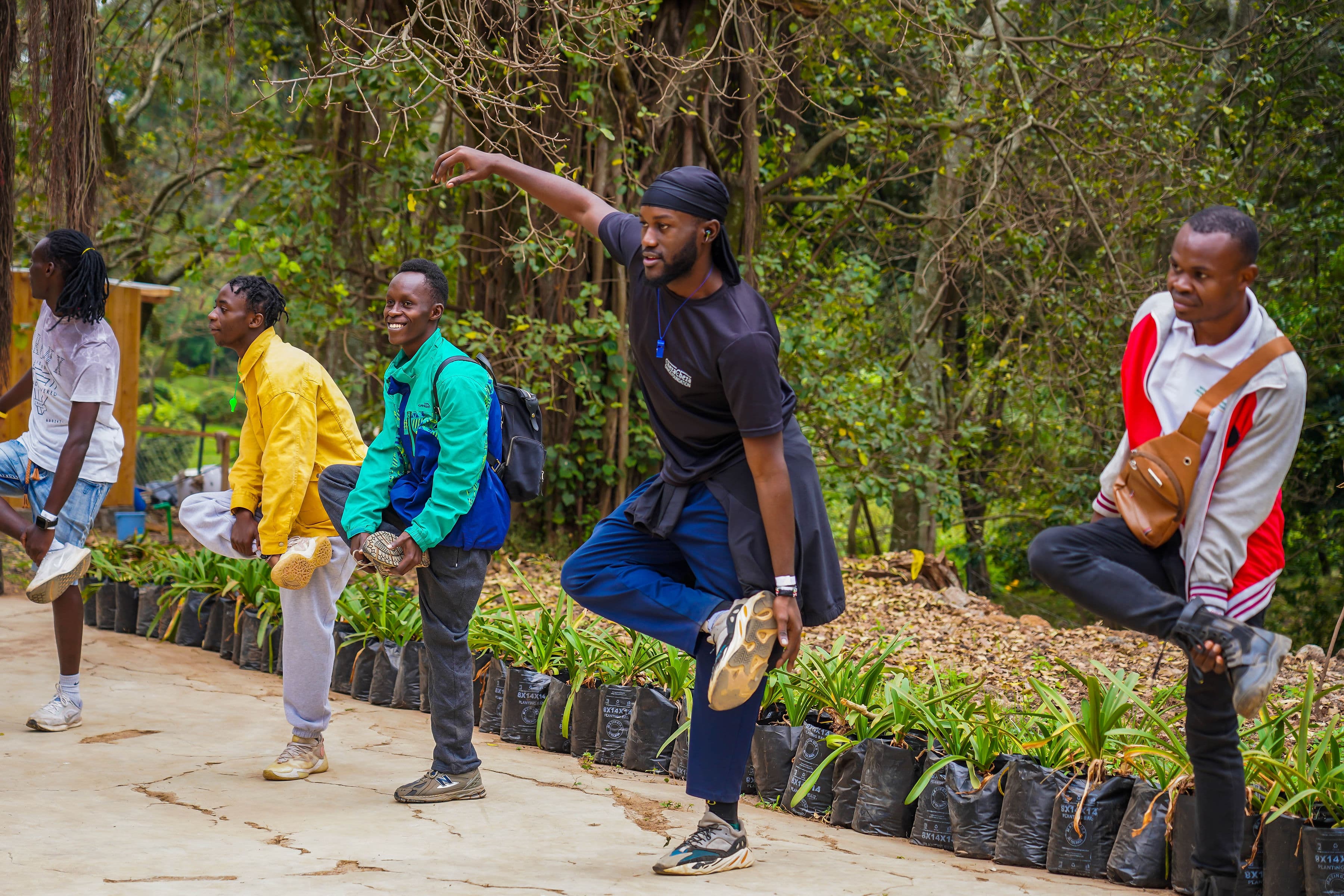 A group stretching in a lunge together on a forest path